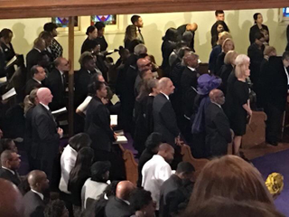 Michelle Obama stands behind former attorney general Eric H. Holder Jr. at services for Gwen Ifill in Washington on Nov. 19. (Credit: Sarah Glover)